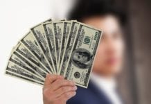 a hand holding a fan of money